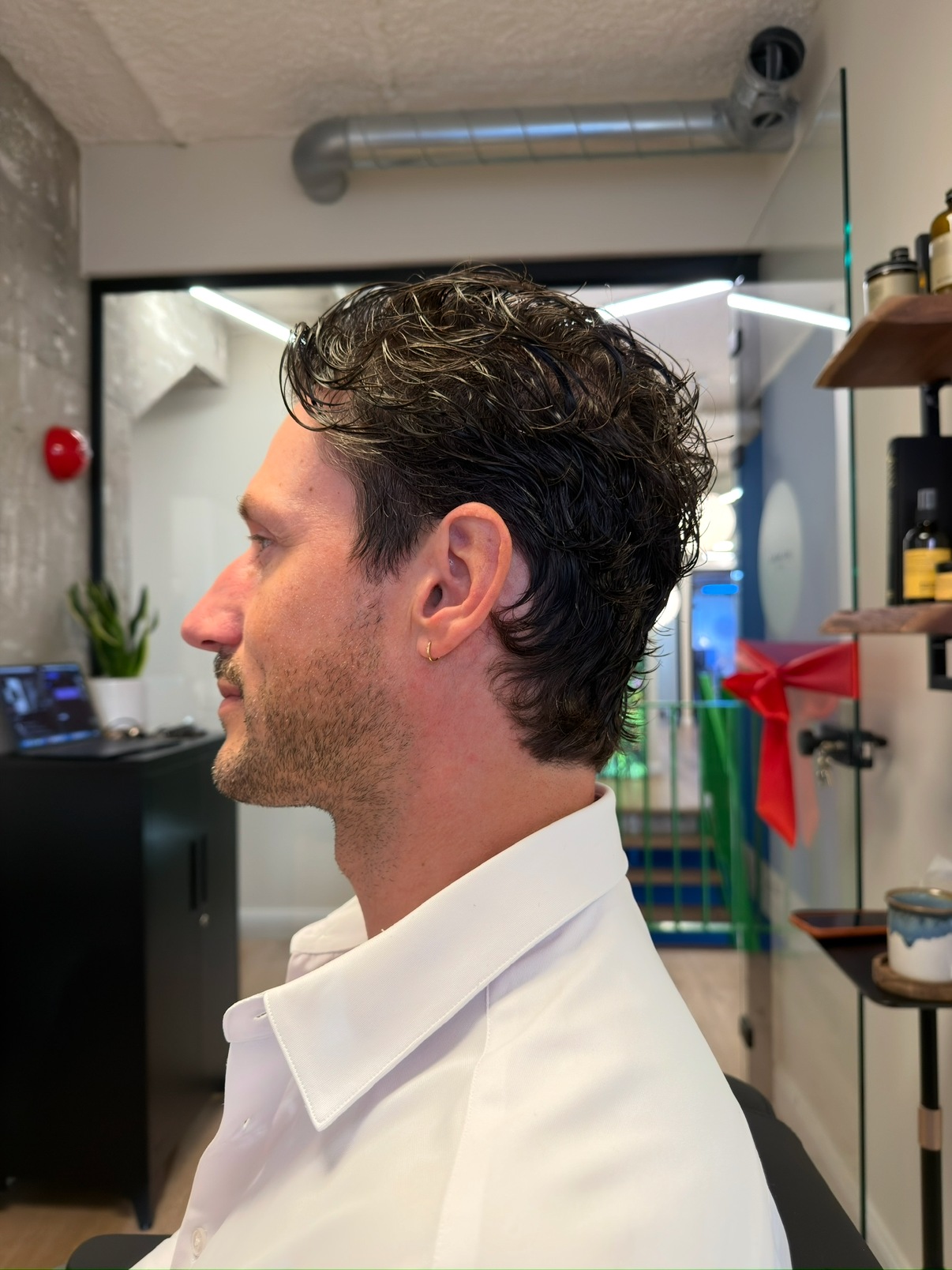Man met krullend bovenhaar en kort geknipte zijkanten, van opzij
